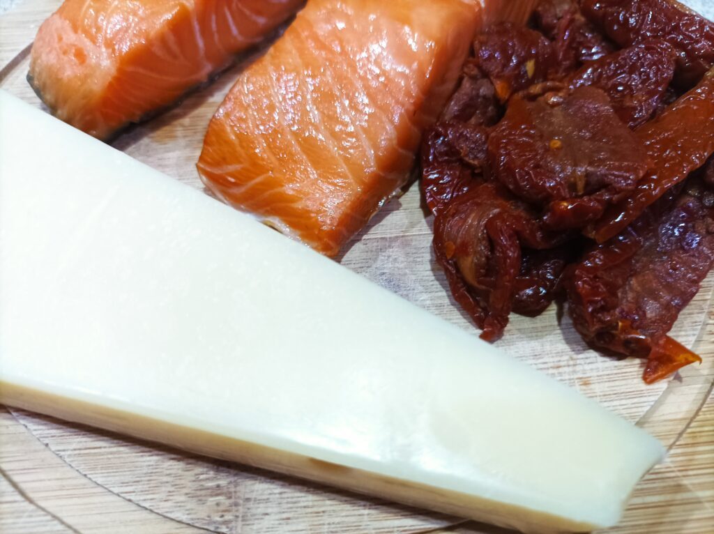 Łosoś wędzony na gorąco i suszone pomidory z parmezanem na drewnianej desce