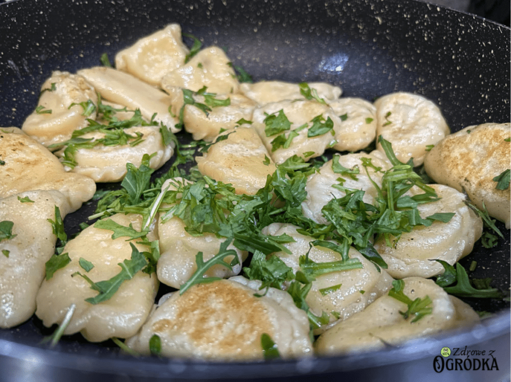 pierogi z bryndzą i ziemniakami i świeża rukola Pierogi z bryndzą i ziemniakami podsmażane na patelni na maśle